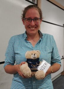 Vicky, smiling and holding the PROMYS Europe mascot, Nick Bear